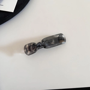 Detailed macro view of smokey grey marble acetate hair clip with gold handmade lettering