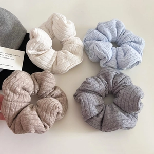Macro detail of knit cable texture hair scrunchies in cream, blue, coffee and grey colors