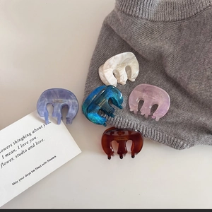 Detail of five mini marble acetate hair claws in pastel colors with Barrette La France text