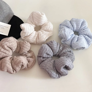 Detail view of chunky knit hair scrunchies in cream, blue, beige, and dark grey textures