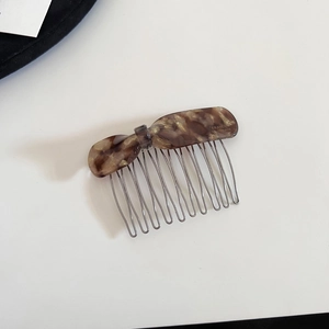 Detailed view of tortoiseshell acetate hair comb with golden glitter and silver metal teeth