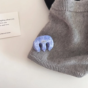 Detail of light purple marble acetate hair claw clip with gold engraving on grey sweater