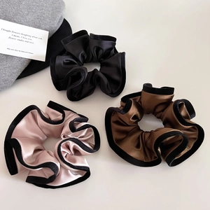 Three-piece set of satin scrunchies in black, brown, and rose pink with velvet trim edges
