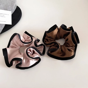 Detailed view of champagne and brown satin hair scrunchies with black velvet piping