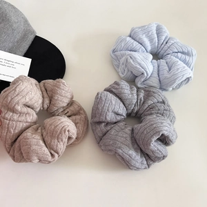 Detailed macro view of cable knit scrunchies in soft grey, pink, and blue textured fabric