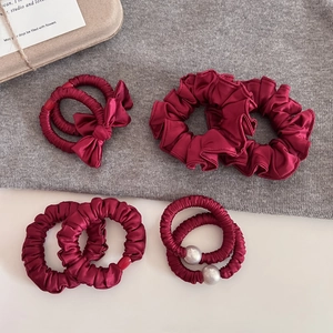 Lot de chouchous en satin rouge vin avec perles et nœuds sur fond gris élégant
