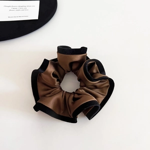 Detail of elegant brown satin hair scrunchie with black velvet trim and soft folds