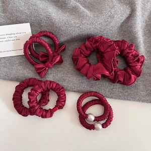 Détail de chouchous en satin bordeaux avec nœuds et élastiques à perles pour cheveux
