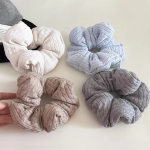 Detailed macro view of four knit scrunchies in cream, blue, brown, and grey soft wool textures