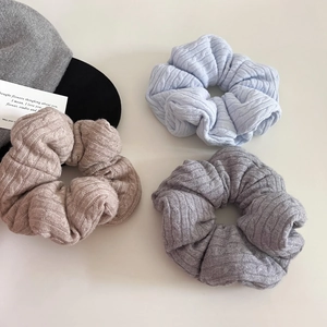 Close-up of cable knit scrunchies in blue, taupe, and grey for autumn hairstyles