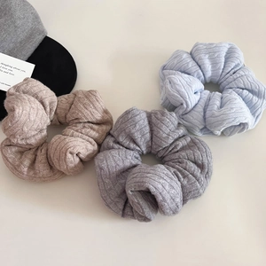 Close-up of cable knit scrunchies in light blue, brown and grey with soft texture