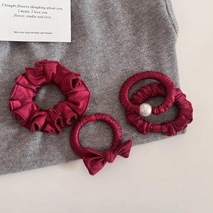 Gros plan détaillé de quatre chouchous en satin bordeaux avec perles et nœuds en soie