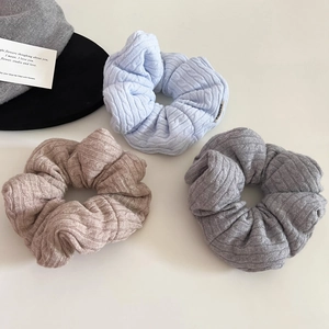 Detailed macro view of three knitted scrunchies in blue, beige, and grey soft wool texture