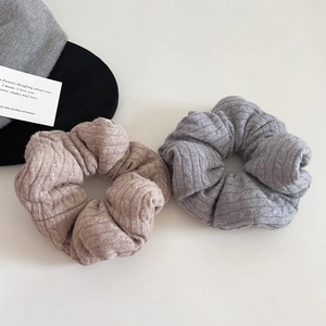 Detail of grey and khaki knitted scrunchies showing soft ribbed texture and plush design