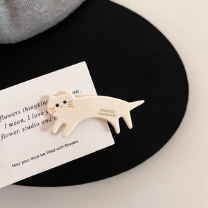 Détail de la pince à cheveux chat en acétate blanc avec moustaches dorées et gravure à la main