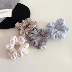 Detail showing cable knit texture and woven labels on various colorful scrunchies