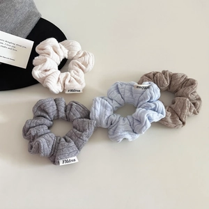 Close-up of four knitted scrunchies in cream, blue, gray, and brown with rib texture