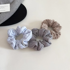 Detailed knit texture of three soft scrunchies in light blue, grey and khaki colors