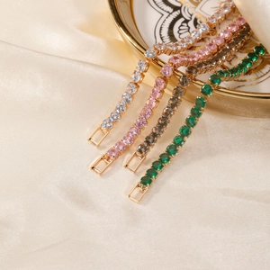 Classic tennis bracelets in four colors hanging on a gold-rimmed ceramic plate