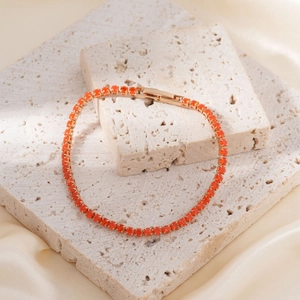 Elegante 18K vergulde tennisarmband met ronde oranje zirkonia op een stenen ondergrond