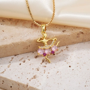 Collana con ciondolo ballerina dorata e cristalli rosa presentata su uno sfondo di seta