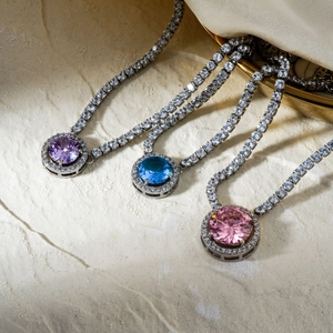 Eleganti collane tennis con zirconi viola, blu e rosa su una superficie in pietra naturale