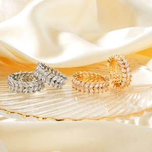 Zweireihige Zirkonia-Ringe in Olivenblatt-Form in Gold und Silber auf Glastablett