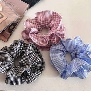 Close-up of three plaid hair scrunchies in pink blue and black checker patterns