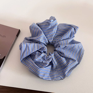 Detail view of a large blue and white striped fabric scrunchie with a pleated French design