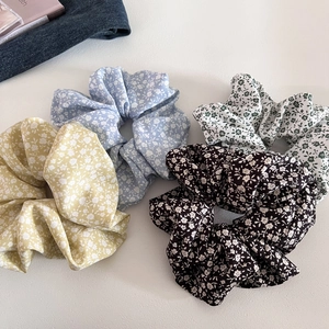 Flat lay of four floral scrunchies in yellow, blue, and brown cotton fabric