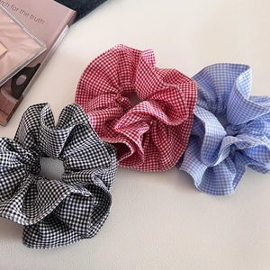 Detailed view of three checkered scrunchies in black, red, and blue plaid cotton fabric