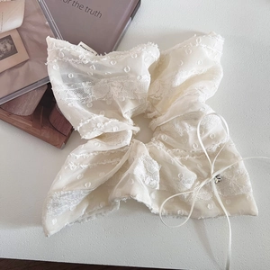 Détail d'un chouchou en dentelle crème avec motif à pois et une petite perle de cristal