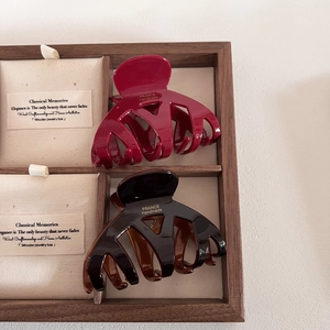 Pinces à cheveux élégantes en acétate bordeaux et marron sur un support en bois chic