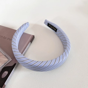 Detailed view of blue striped fabric headband with classic preppy pattern and woven label