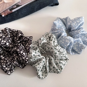 Detailed macro view of three floral fabric scrunchies in black, green, and blue patterns