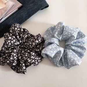 Flat lay of floral pattern scrunchies in black and blue on white textured background