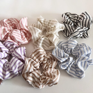 Detail of six colorful striped scrunchies in pink, cream, purple, and blue fabric