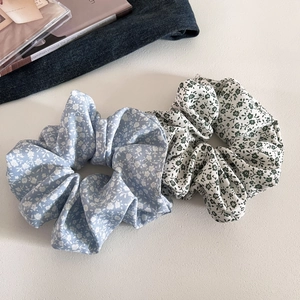 Detail showing blue and white floral scrunchies made of soft fabric on a textured surface