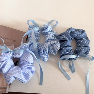 Detailed view of three blue checkered and polka dot hair scrunchies with elegant ribbons