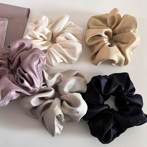 Detailed view of five colors of premium satin silk scrunchies set on white background