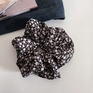 Detailed texture of black floral fabric scrunchie with delicate white flower patterns