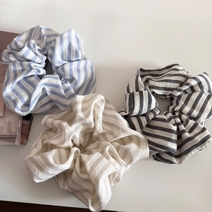 Three-piece large striped fabric scrunchies in blue, beige, and black for elegant hairstyling