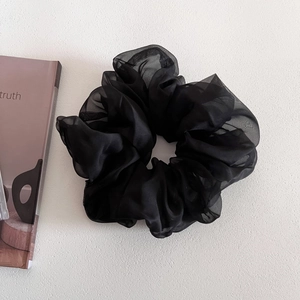 Detail of a large black mesh scrunchie featuring elegant organza texture and soft pleats