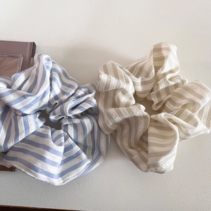 Striped oversized fabric scrunchies in blue and cream colors on a white surface