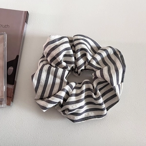 Detailed view of black and white striped fabric scrunchie on a clean white surface