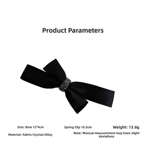 Detail view of a black satin bow hair clip with rhinestone center and metal spring clip