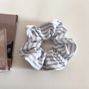 Close-up of a blue and white striped fabric scrunchie with breathable cotton texture