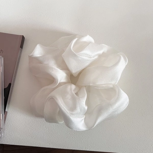 Macro shot of white oversized pearlescent tulle scrunchie with layered pleated texture