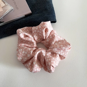Detail of pink floral scrunchie with white flower print on a stylish textured background