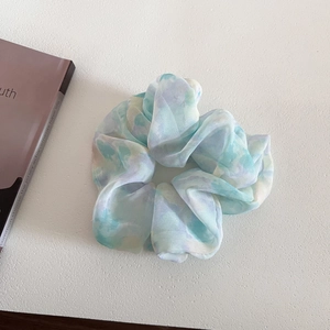 Detail of airy chiffon scrunchie with soft blue-green tie-dye watercolor floral pattern